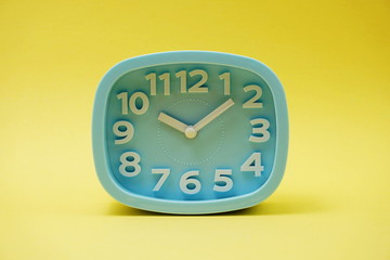 light blue alarm clock on yellow background