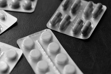 Pills and tablets blisters on a dark background close up black and white