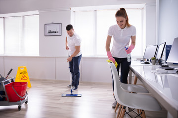 Wall Mural - Smiling Two Young Janitor Cleaning The Office