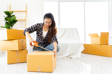 hipster young girls packing cardboard box. Moving boxes and household stuff in modern room. Delivery Asian woman packing, moving boxes at new home for customer. service, moving and transportation