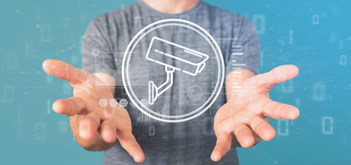 Poster - Businessman holding Security camera system icon and statistics data - 3d rendering