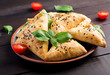 Asian food. Samsa (samosa) with chicken fillet and green herbs on wooden background.