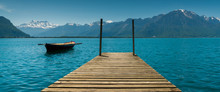 Mountain And Lake Landscape With A Vintage Rescue Rowboat And A Wooden Pier