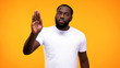 © motortion - Young black guy showing stop gesture with palm on yellow background, rejection