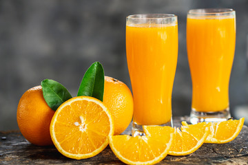 orange sliced and orange juice glasses with green leaf on wooden table 