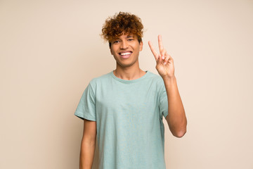 African american man with green shirt smiling and showing victory sign