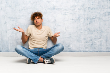 Wall Mural - Young african american man sitting on the floor unhappy for not understand something