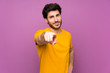 © luismolinero - Handsome over isolated purple wall points finger at you with a confident expression