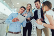 © Mediteraneo - Group of businesspeople using a digital tablet together in office building