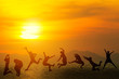 © tawanlubfah - Young friends having fun on the beach and jumping against a sunset on summer.