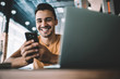 © BullRun - Portrait of happy hipster blogger with modern mobile phone in hands smiling at camera while laughing from funny joke on website, millennial cheerful man with digital technologies enjoying leisure time