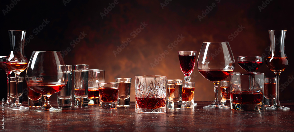 Set of strong alcoholic beverages in glasses on a brown background. - obrazy, fototapety, plakaty 