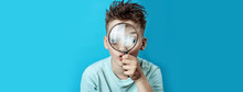 Boy In A Light T-shirt Looking Into A Large Magnifying Glass