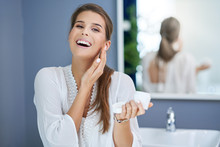 Beautiful Brunette Woman Applying Face Cream In The Bathroom
