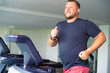 © Евгения Медведева - smiling full male runs on a treadmill in a gym. concept of weight loss and sport. side view.