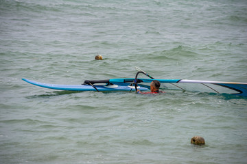 windsurfer with a board on a tropical beach, makes water start