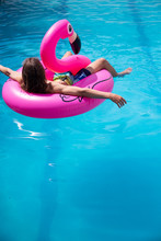 Young Man Floating In A Inflatable Flamingo In A Blue Pool A Sunny Day Of Summer Vacation