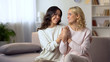Smiling homosexual female couple holding hands on sofa at home, happy together
