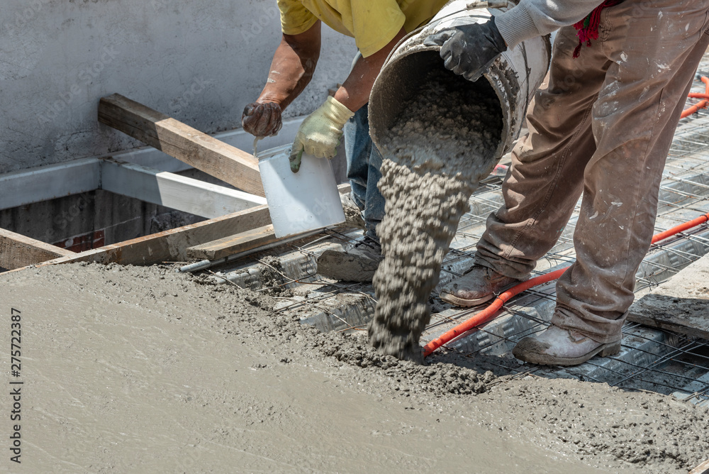Pouring concrete at a construction site. Filling a rooftop with cement over the pipelines - obrazy, fototapety, plakaty 