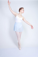 Cute Caucasian Girl In Ballet Clothes Learning To Be A Ballerina On A White Background In The Studio. Plus Size Young Woman Dreams Of Being A Dancer.