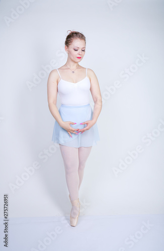 cute caucasian girl in ballet clothes learning to be a ballerina on a white  background in the Studio. plus size young woman dreams of being a dancer. -  Buy this stock photo