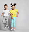 © FAB.1 - Two excited kids in fashion outfits, jumping over the light background. Sister and brother, friends in fashionable clothes