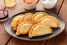 A Closeup Of Argentinian Empanadas With Sauces And Wine On A Dark Rustic Wooden Background