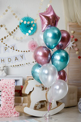 A large bunch of balloons pink and green. Birthday pink and teal decorations with gifts, toys, garlands and candy for yearling little baby party on a white background.