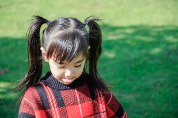 Portrait of cute Little asian girl in moment of happiness with grass background .Children wear sweaters.