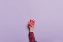 Time Management, Punctuality, Awakening Concept. Unrecognizable Man Holds Little Red Alarm Clock In Hand, Shows How Much Time Left, Isolated On Purple Wall. Timekeeper With Mechanical Watch.
