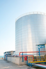 Industrial stainless steel chemical storage tanks or silo in factory or facility. Oil or fuel silo in factory. Liquid metal petroleum container.