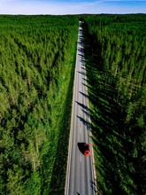 Aerial View Of A Country Road With Red Car In The Middle Of Green Summer Forest