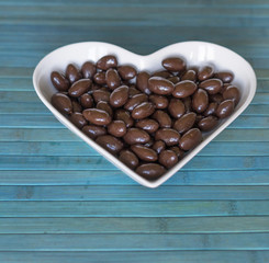 Wall Mural - Nuts arranged in heart shape on background. Food image close up candy, chocolate milk, extra dark almond nuts. Love Texture