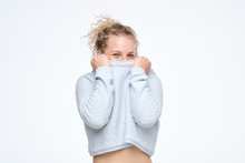 Curly Blonde Girl Pulling Sweater Over Head Having Fun Being Shy And Childish, Disappearing In Her Clothes Looking From Underneath.