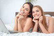 © Viktoriia - Friends together at home lying on bed with laptop posing to camera joyful