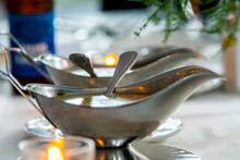 Detailed Shot Of Luxury Silver Gravy Bowls Containing Salad Dressing At A Banquet For A Wedding Party.  The Romantic Dinner Is Elegant With White Table Cloth And Decorative Plate Wear