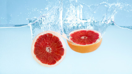 Aufkleber - Fresh cut grapefruit falling in water with splash