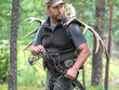 © Stavros - A hunter with a bow in the woods carries moose horns on his back and looking by side