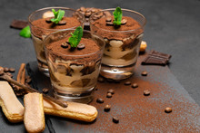 Classic Tiramisu Dessert In A Glass And Savoiardi Cookies On Dark Concrete Background