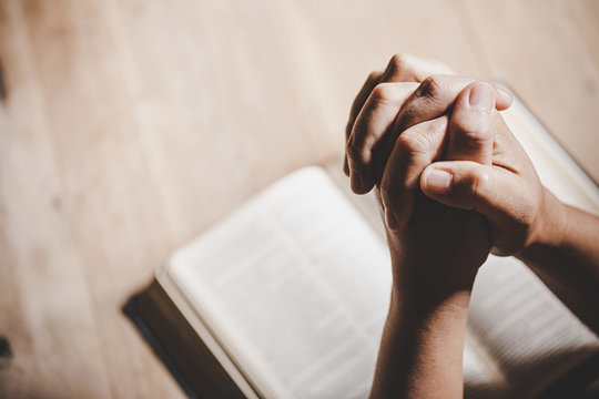 spirituality and religion, hands folded in prayer on a holy bible in church concept for faith.