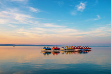 Colorful Sunset Over Lake Balaton With Pedalos, Kayaks And A Boat In The Foreground In Hungary