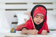 Young muslim girl writing a book, islamic child do homework at home