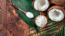Top View Of Coconut MCT Oil In Bowl And In Spoon And Halved Coco-nut On Wooden Table. Health Benefits Of MCT Oil. MCT Or Medium-chain Triglycerides, Form Of Saturated Fatty Acid. Flat Lay. Copy Space