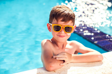 Wall Mural - Kid boy with sun protection cream on his skin in the pool. Children, summer, holiday and healthcare concept