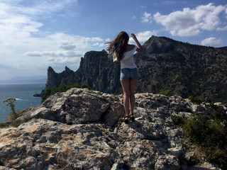 Rocky seashore under the sunlight. Crimean mountains covered with forest. Girl in the mountains. Trekking in the mountains.