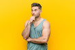 © Asier - Young fitness man against a yellow background looking sideways with doubtful and skeptical expression.