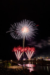 Imagen vertical de mucha gente observando los fuegos artificiales sobre el puente en el río con la ciudad vieja al lado