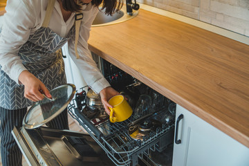 Wall Mural - young pretty woman putting dishes in dishwasher