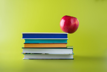 Apple balancing on the edge of a pile of books. Education concept