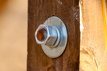 New shiny nut and two flat metal washers on the rusty bolt in the wooden board